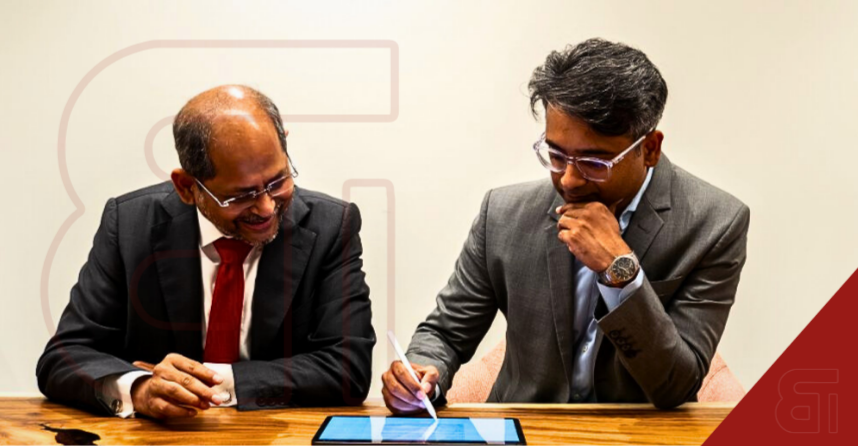 Ramki Jayaraman of Synarchy Consulting and Aditya Pisupati of Mordor Intelligence signing the strategic alliance agreement on a tablet.