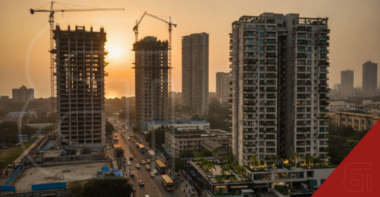 Aerial view of Mumbai property market construction site at sunset with cranes building high-rise apartments near busy roads.