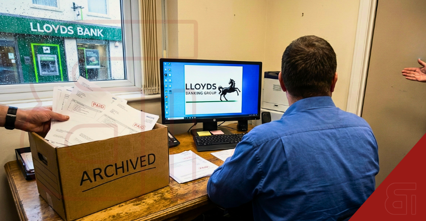 Office setting featuring a Lloyds Banking Group computer screen and a box of archived invoices, symbolizing the closure of the bank's SME invoice factoring service.